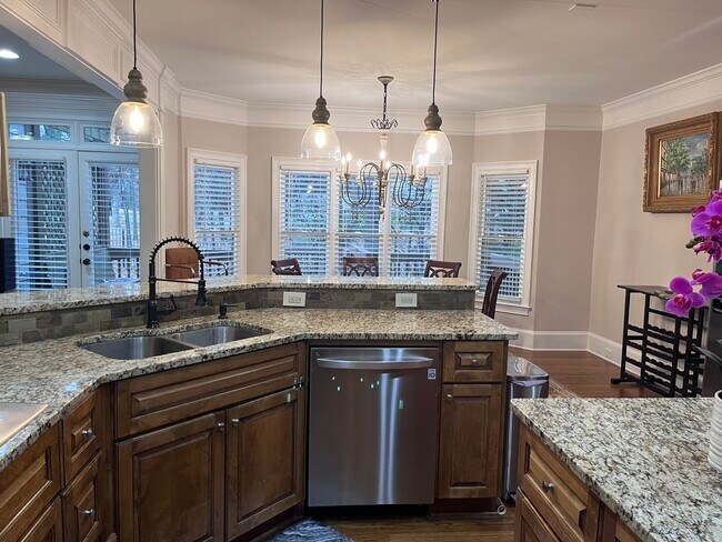 Kitchen - Kitchen with dark wood-type flooring, sink, stainless steel dishwasher, and hanging light - 7987 Magnolia Sq