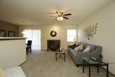 This single-floor residence offers a well-organized layout with distinct living, dining, kitchen, and sleeping areas. The living room serves as a central gathering space, featuring plush carpeting, a ceiling fan with light fixture, and a tile-surround fireplace as a focal point. Large sliding glass doors with vertical blinds allow natural light to fill the room and provide outdoor views. Adjacent to the living room, the dining area accommodates a full table setting beneath a pendant light, with its own sliding glass door access adding brightness and connectivity to the outdoors.

The galley-style kitchen is efficiently designed with warm oak cabinetry lining both walls, providing generous storage and counter space. White appliances, including a range, refrigerator, dishwasher, and built-in microwave, equip the space thoroughly. A hallway off the kitchen leads to in-unit laundry facilities, adding everyday convenience.

Both bedrooms are carpeted and include ceiling fans. The primary bedroom features mirrored sliding closet doors and direct access to a full bathroom, which includes a single-sink vanity with oak cabinetry, a wall mirror, and a shower-tub combination. Textured ceilings are consistent throughout the unit, contributing to a cohesive, comfortable ambiance.