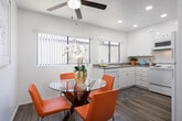 Located at 4 Austin in Irvine, CA, this single-story residence offers a well-designed layout with a blend of comfort and functionality. The living room is a standout space, showcasing striking vaulted ceilings with exposed white-painted beams that lend an airy, open feel. Sliding glass doors lead directly to a private outdoor deck overlooking lush greenery, seamlessly extending the living area outdoors. The kitchen is thoughtfully appointed with white cabinetry, granite countertops, recessed lighting, and white appliances, complemented by wood-look flooring and a bright window. An adjacent dining area features the same wood-look flooring, a ceiling fan, and a light-filled window. The primary bedroom includes mirrored closet doors, a ceiling fan, and direct access to an en suite bathroom featuring granite countertops, white cabinetry, and a large vanity mirror. A secondary bedroom offers plush carpeting, a mirrored closet, and generous natural light. A full bathroom serves the remaining rooms, complete with granite countertops, a tub-shower combination, and wood-look flooring. Throughout the home, crisp white walls and neutral tones create a bright, cohesive atmosphere ideal for comfortable living in the heart of Irvine.