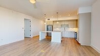 Located at 468 Quay Commons in downtown Sarasota, Florida, this single-floor residence offers five bedrooms, two bathrooms, and a thoughtfully designed open layout. The combined kitchen and living area serves as the heart of the home, featuring light-toned hardwood-style flooring, a ceiling fan, and recessed lighting throughout. The kitchen is appointed with sage-green shaker cabinetry, a white quartz center island, a classic tile backsplash, stainless steel appliances including a refrigerator, range, and microwave, and elegant pendant lighting that adds a refined touch.

The bedrooms are bright and airy, each featuring the same warm hardwood-style flooring, ceiling fans, and window blinds that allow for natural light control. Select bedrooms offer access to a private balcony with sweeping city views of Sarasota's skyline. The hallway connecting the rooms is clean and well-lit with recessed lighting, maintaining the home's modern, minimalist aesthetic.

The bathrooms are finished with tile flooring and include glass-enclosed walk-in showers with built-in benches and dark bronze hardware accents. Two closets provide organized storage with wire shelving systems. A dedicated in-unit laundry room houses a full-size Whirlpool front-loading washer and dryer, adding everyday convenience to this well-appointed Sarasota residence.
