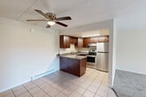 This one-bedroom, one-bathroom unit in Bensenville, Illinois offers a well-organized layout across a single floor. The open-concept living and kitchen area is a central highlight, featuring tile flooring that flows seamlessly between the two spaces. The kitchen is equipped with rich dark wood cabinetry, granite countertops, a peninsula with additional counter space, and a full suite of stainless steel appliances including a refrigerator, electric range, and integrated ventilation. A ceiling fan with a built-in light fixture anchors the adjacent living area, which also includes baseboard heating along the walls.

The living room is carpeted and benefits from natural light through a large sliding glass door that opens to a balcony, offering outdoor views. The spacious primary bedroom features soft carpet, a window with vertical blinds, and baseboard heating. It provides direct access to both a dedicated walk-in closet with built-in shelving and rods, and the full bathroom. The bathroom includes a clean white tub-shower combination and a vanity with a granite countertop and dark wood cabinetry. The overall aesthetic is functional and well-maintained, with a neutral color palette throughout.