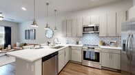 Located at 600 Stewarts Ferry Pike in Nashville, TN, this well-appointed one-bedroom, one-bathroom residence offers a thoughtfully designed single-floor layout. The open-concept kitchen and living area serves as the heart of the home, where the kitchen impresses with light gray flat-front cabinetry, crisp white quartz countertops, a classic subway tile backsplash, and a full suite of stainless steel appliances including a range, microwave, dishwasher, and refrigerator. A peninsula with seating provides a casual dining option beneath stylish pendant lighting. The living room extends naturally from the kitchen, featuring wood-style flooring, high ceilings, a ceiling fan, and large windows dressed with floor-to-ceiling drapes that flood the space with natural light and offer views of the surrounding area. The bedroom is a comfortable retreat with plush carpeting, generous natural light from a large window, and access to a dedicated closet. The bathroom features a glass-enclosed walk-in shower with subway tile surround, a single-sink vanity with modern cabinetry, and wood-style flooring that ties the space together. Throughout, neutral tones and contemporary finishes create a clean, cohesive aesthetic suited for modern living.