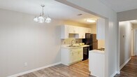 Located at 3722 Walton Way Ext in Augusta, Georgia, this single-floor residence offers two bedrooms and three bathrooms within a well-organized, efficiently laid-out floor plan. The living room greets you with wood-look flooring and neutral-toned walls, illuminated by a stylish multi-bulb chandelier that adds a warm, inviting ambiance to the space. An open archway connects the living area directly to the kitchen, which features a galley-style design with crisp white shaker cabinetry, light marble-look countertops, a classic tile backsplash, and black appliances including a refrigerator, range, dishwasher, and over-the-range microwave. The bedrooms are carpeted in soft, neutral tones, offering a comfortable retreat. The primary bedroom provides a generously sized layout with ample wall space. The bathrooms are finished with white shaker vanities, marble-look countertops, and wood-look flooring, maintaining a consistent, clean aesthetic throughout. A dedicated laundry room houses a full-sized washer and dryer. A hallway and closet round out the floor plan, providing practical storage solutions. The textured ceilings and neutral color palette throughout create a cohesive, move-in-ready environment.