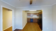 Located at 221 E. Main in Carmel, Indiana, this two-floor space offers a well-considered layout with functional design elements throughout. The main living area features rich hardwood flooring that extends seamlessly into the kitchen, creating a cohesive and warm aesthetic. Crown molding adds a refined architectural detail along the upper edges of the walls, contributing to a polished interior feel.

The kitchen is tucked within a defined recessed alcove, providing a sense of separation while maintaining an open connection to the living area. It is outfitted with medium-toned wood cabinetry, stone-look countertops, and a full suite of black appliances including a refrigerator, range, and dishwasher. A utility sink and overhead fluorescent lighting complete the practical setup. A ceiling fan is installed in the adjacent living space, supporting air circulation and comfort. The neutral wall tones throughout lend a clean, versatile backdrop suitable for a variety of uses. With two floors, the space offers flexibility in how the levels can be utilized, making it a functional option in the heart of Carmel.