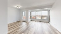 Located at 333 Rue Riverside in Saint-Lambert, Quebec, this well-appointed 2-bedroom, 1-bathroom unit offers a clean, modern aesthetic throughout its thoughtfully designed layout. Light-toned hardwood flooring flows consistently across the main living areas, complementing the crisp white walls and creating a bright, cohesive atmosphere.

The combined dining and living area is generously proportioned, bathed in natural light through a large bank of windows that frame views of the surrounding neighbourhood. A sliding door provides direct access to a private balcony, extending the living space outdoors. The kitchen features warm honey-toned wood cabinetry extending to the ceiling for ample storage, stainless steel appliances including a refrigerator and dishwasher, and neutral countertops over tile flooring.

The primary bedroom is a comfortable, well-sized retreat with its own closet, while the second bedroom benefits from a corner window that draws in natural light. Both rooms feature the same warm hardwood flooring found throughout. Two closets provide practical storage across the unit.

The bathroom is finished with white tile surrounding a full bathtub and shower, complemented by a warm wood vanity with an integrated sink and overhead cabinetry. A hallway connects the rooms efficiently, completing this well-organized and move-in ready home.