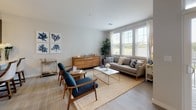 Located at 265 Communication Way in Hyannis, MA, this thoughtfully designed single-floor residence offers a seamless blend of modern style and comfortable living. The open living area is bathed in natural light from large windows with white blinds, showcasing light hardwood-style flooring that flows throughout the space. Coastal-inspired décor accents complement the neutral color palette, creating a warm and inviting ambiance.

The kitchen is a standout feature, equipped with stainless steel appliances including a gas range, microwave, and French door refrigerator. Contemporary wood-grain cabinetry extends to the ceiling for ample storage, while quartz countertops and a subway tile backsplash add a polished finish. A deep undermount sink and pendant lighting complete the space.

The primary bathroom offers a spacious, elongated layout with dual-tone wood-grain vanity cabinetry, quartz counters, and a glass-enclosed shower with tile surround. It connects directly to a walk-in closet with built-in shelving and hanging storage. A second bathroom mirrors the same refined finishes, featuring a matching vanity and light hardwood flooring. The overall design reflects a clean, contemporary aesthetic well-suited to the Cape Cod coastal setting.