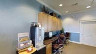 Located on Donerail Way in Raleigh, NC, this single-story space is designed to support productivity and convenience. The interior is finished with soft blue-gray walls, white crown molding, and recessed lighting that creates a bright, professional atmosphere. Carpeted flooring adds warmth underfoot throughout the space.

The business center area is well-equipped, featuring a built-in workstation with a desktop computer, keyboard, and task lighting, complemented by ergonomic leather office chairs. Above the workstation, a bank of warm wood cabinetry provides generous storage, with decorative accessories displayed on top. The upper cabinets are paired with a continuous countertop surface, offering additional workspace.

A coffee and refreshment station is positioned nearby, complete with a Starbucks-branded coffee machine, a dedicated condiment and supply organizer, and convenient counter space for self-service use. The area is thoughtfully arranged to make it easy for multiple users at once.

Overall, the space maintains a clean, polished aesthetic with functional furnishings, organized storage, and a welcoming ambiance suited for a community or professional setting.