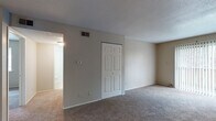 Located at 1645 SW 37th Terrace in Topeka, Kansas, this single-floor unit offers a practical and well-organized layout designed for comfortable everyday living. The living area is generously sized, featuring neutral-toned carpet, a ceiling fan with light fixture, and a sliding glass door that allows natural light to flow in while providing outdoor access. The space connects openly to the kitchen, which is a notable highlight of the unit. The kitchen is outfitted with dark cabinetry, granite-style countertops, stainless steel appliances including a refrigerator and range, and tile flooring, creating a functional and stylish cooking environment.

The bedrooms are carpeted and well-proportioned, each featuring windows with blinds that bring in natural light. Closet storage is well-represented throughout, with both standard and double-door closet configurations providing ample room for personal storage. One bedroom features vertical wood panel wall detail, adding a subtle design element.

The bathrooms are finished with tile flooring, dark vanity cabinetry, and light-toned countertops. One bathroom includes additional open shelving, enhancing storage utility. Textured ceilings are consistent throughout the unit, contributing to its classic residential character. Overall, the space presents a clean, neutral palette well-suited for a variety of furnishing styles.