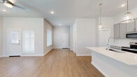 Located at 2600 Lake Forest Dr in McKinney, TX, this well-designed two-story home offers three bedrooms and three full bathrooms across two thoughtfully laid-out floors. The main level features an open-concept kitchen and living area bathed in natural light from large, blinds-fitted windows. The kitchen is equipped with gray shaker-style cabinetry, white quartz countertops, a subway tile backsplash, stainless steel appliances, and a kitchen island with an undermount sink and pendant lighting — combining functionality with a clean, modern aesthetic. Warm wood-look flooring flows throughout both levels, lending a cohesive and inviting feel to the entire home. The living area is open and airy, with recessed lighting and a smooth transition to the entryway. Upstairs, the spacious primary bedroom includes a walk-in closet and ceiling fan, while the additional bedrooms are well-proportioned, each featuring ceiling fans and natural light. The bathrooms are finished with gray vanity cabinetry, white quartz counters, and wood-look flooring, with one bath offering a full tub-shower combination with white tile surround. Clean lines, neutral tones, and modern fixtures throughout give this home a bright, contemporary character.