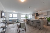 Located at 100 Manett Crescent in Brampton, Ontario, this modern 3-bedroom, 1-bathroom unit offers a thoughtfully designed layout that maximizes every square foot. The open-concept kitchen and living area serves as the heart of the home, featuring light wood cabinetry, a large center island with quartz countertop and bar seating, stainless steel appliances including a refrigerator and range, and a white subway tile backsplash. Light hardwood flooring runs throughout, lending warmth and continuity to the space. Large floor-to-ceiling windows in the living and dining area flood the unit with natural light and frame sweeping panoramic views of the Brampton skyline and surrounding greenery. The three bedrooms are bright and well-proportioned, with the secondary bedrooms benefiting from expansive corner windows that offer impressive elevated city views. The bathroom features a full soaker tub and shower combination with elegant marble-look tile surround. A dedicated in-unit laundry area with a stacked washer and dryer adds everyday convenience. Clean white walls, recessed lighting, and a neutral palette throughout create a fresh, contemporary ambiance that is both functional and inviting.
