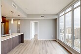 Located in Edmonton's vibrant Oliver neighbourhood, this contemporary 2-bedroom, 2-bathroom unit offers a thoughtfully designed open-concept layout finished with high-end materials throughout. The combined kitchen and living area serves as the heart of the home, anchored by a striking oversized waterfall quartz island with a double undermount sink and three elegant pendant lights overhead. The kitchen features two-tone cabinetry — crisp white upper cabinets paired with rich dark wood lowers — complemented by stainless steel appliances and a classic subway tile backsplash. Light hardwood-style flooring runs seamlessly throughout the unit, enhancing its bright, airy feel. The living area is bathed in natural light through expansive floor-to-ceiling windows that frame sweeping panoramic views of the Edmonton skyline. Both bedrooms continue this connection to the outdoors, with large windows offering elevated city vistas. The primary bathroom is a refined retreat, showcasing full-height marble-look tile in the glass-enclosed walk-in shower, matching marble flooring, and a floating vanity with an integrated sink. The second bathroom features a soaker tub-shower combination with coordinating marble-effect surrounds. Neutral grey tones and clean architectural lines lend the entire space a polished, modern ambiance.