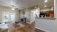 Located at 5751 Green Hill Rd in San Angelo, TX, this well-appointed 1-bedroom, 2-bathroom residence offers a thoughtfully designed single-floor layout. The open-concept living, dining, and kitchen area serves as the heart of the home, featuring rich hardwood-style flooring, neutral warm-toned walls, and a ceiling fan overhead. French doors in the living room invite natural light and provide outdoor access. The kitchen is outfitted with dark wood cabinetry, granite-style countertops, black appliances, and a breakfast bar that connects seamlessly to the dining area. A dedicated dining nook with hardwood-style flooring provides an ideal space for meals. The bedroom offers plush carpeting, a striking accent wall, a ceiling fan, and a large window that fills the room with natural light. A dedicated office features its own window, carpet flooring, and a vibrant accent wall, offering a functional workspace. Both bathrooms are finished with dark wood vanities, granite-style countertops, and tile flooring, with one bathroom featuring a tiled tub-shower combo. A hallway and closet provide practical storage solutions. The overall ambiance is warm, modern, and inviting throughout.