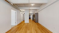 Located at 107 N Queen St in the heart of downtown Lancaster, PA, this thoughtfully designed one-bedroom, one-bathroom unit blends industrial-chic character with modern comfort. The open living area makes a striking first impression with soaring exposed ceilings featuring corrugated metal decking and structural beams, warm-toned hardwood flooring, and an abundance of natural light streaming through large windows that frame views of the historic surrounding streetscape.

The galley-style kitchen is well-appointed with dark gray cabinetry, white quartz countertops, stainless steel appliances including a range, dishwasher, and refrigerator, all tied together by the continuous hardwood flooring. Exposed ductwork and track lighting add to the unit's urban loft aesthetic.

The bedroom offers a comfortable retreat with plush carpeting, a large window with views of neighboring brick architecture, and access to a dedicated closet with hanging storage. A barn-style sliding door accents the space with a nod to contemporary design.

The bathroom features tile flooring, a dark wood vanity with a white countertop, and clean, neutral finishes. A convenient in-unit washer is tucked neatly into a dedicated hallway space. Two hallways connect the rooms efficiently, completing this well-planned urban residence.