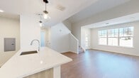 Located at 9 Monticello Dr in Brewster, NY, this thoughtfully designed one-bedroom, one-bathroom home offers a clean, modern aesthetic with high-quality finishes throughout. The open-concept kitchen and living area forms the heart of the home, featuring light wood-tone cabinetry extending to the ceiling, a white subway tile backsplash, stainless steel appliances including a range, microwave, and refrigerator, and a quartz waterfall island with pendant lighting. Warm hardwood flooring flows seamlessly through the space, complementing the bright, neutral palette. The living area is anchored by large windows that invite abundant natural light and offer outdoor views. A staircase connects the main level to the upper floor. The generously sized bedroom features a large window with outdoor views and hardwood floors, creating a bright and airy retreat. A spacious walk-in closet with wire shelving and in-unit laundry hookups provides excellent storage. The full bathroom is appointed with a soaking tub, stone-tile surround, a wood-tone vanity with quartz countertop, and modern fixtures. Clean white panel doors and recessed lighting complete this well-appointed home.