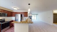This single-floor residence offers a thoughtfully designed open-concept layout that seamlessly connects the kitchen and living areas. The kitchen is equipped with rich, warm-toned cabinetry, stainless steel appliances including a French door refrigerator, electric range, and over-the-range microwave, complemented by granite countertops and hardwood flooring. A peninsula with pendant lighting serves as a natural divider between the kitchen and the expansive carpeted living room, which features a tile-surround fireplace with a dark mantel and a sliding glass door that invites natural light and outdoor views.

The bedrooms are generously sized, with plush carpeting, neutral wall tones, and ample natural light from well-placed windows offering views of the surrounding greenery. The bathrooms are clean and functional — one features a vanity with gray cabinetry and black hardware accents with a walk-in shower, while the second includes warm wood cabinetry and a full bathtub and shower combo. A dedicated laundry room houses a full-size washer and dryer with overhead cabinetry for added storage. The overall ambiance is bright, clean, and move-in ready, offering a comfortable and practical living environment.