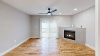 Located at 30 Madelyn Way in Laconia, NH, this well-designed two-bedroom, one-bathroom home spans three floors and offers a clean, modern aesthetic throughout. The entry-level garage features a polished concrete floor, an automatic opener, built-in wall storage, and direct interior access — providing both practicality and convenience.

The main living floor showcases an open-concept kitchen and living area with warm hardwood flooring and recessed lighting. The kitchen is equipped with gray shaker-style cabinetry, white quartz countertops, a white subway tile backsplash, and a full suite of stainless steel appliances, including a side-by-side refrigerator with ice and water dispenser, electric range with over-the-range microwave, and dishwasher. The living area is anchored by a tile-surround gas fireplace and features a ceiling fan and sliding glass door that fills the space with natural light.

The upper floor hosts two carpeted bedrooms, each with ceiling fans and soft neutral tones. The primary bedroom includes a closet, while the second bedroom benefits from a large window. The shared bathroom offers tile flooring, a white quartz vanity, and matte black fixtures, lending a contemporary touch. The layout is completed by hallways and a staircase connecting all three levels seamlessly.