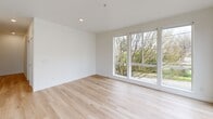 Located at 8770 N Willamette Blvd in Portland, OR, this thoughtfully designed one-bedroom, one-bathroom unit offers a clean, modern aesthetic throughout its single floor. Light hardwood flooring flows continuously through every room, creating a warm and cohesive feel.

The open-concept living, dining, and kitchen area is a standout feature, with expansive floor-to-ceiling windows on multiple walls flooding the space with natural light and offering views of the surrounding Portland neighborhood and greenery. The kitchen is well-appointed with stainless steel appliances including a refrigerator, range, microwave, and dishwasher, complemented by white upper cabinetry, light wood lower cabinets, a hexagonal tile backsplash, and clean quartz-style countertops.

The bedroom is a bright and serene retreat with a tall vertical window and a sliding double-door closet, while an additional closet provides extra storage. The combined bathroom and laundry room features a glass-enclosed shower, a white vanity, and an in-unit washer and dryer. A dedicated entrance hallway with recessed lighting leads into the unit, completing a practical and polished layout ideal for comfortable single-floor living.