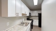 This renovated one-bedroom, one-bathroom residence with a den offers a thoughtfully updated single-floor layout designed for comfortable everyday living. The kitchen has been fully refreshed and features white shaker-style cabinetry with brushed nickel hardware, light granite-patterned countertops, a stainless steel sink with a modern pull-down faucet, wood-look plank flooring, and a full suite of black appliances including a gas range, microwave, and refrigerator. Ample upper and lower cabinet storage ensures excellent functionality throughout the space. The bedroom is generously proportioned, finished with soft wall-to-wall carpeting and neutral gray tones, and benefits from a window that invites natural light. The den provides a flexible additional room, also carpeted and naturally lit, suitable for use as a home office, guest space, or hobby room. The bathroom is clean and well-appointed, featuring a full tub-shower combination with white tile surround, a white vanity, and dark hardwood-style flooring that adds a grounding contrast. Throughout the unit, neutral color palettes and updated finishes create a cohesive, move-in-ready atmosphere that balances practicality with modern style.
