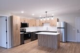 This contemporary apartment, located at Alex 114, offers a well-designed living space of 830 square feet. The single-floor layout comprises two bedrooms, including a generous primary bedroom of 180 square feet, and two full bathrooms. The heart of the home is the open-concept kitchen, which showcases a blend of light and dark cabinetry, stainless steel appliances, and a convenient island. White subway tile backsplash and quartz countertops add a touch of elegance. The kitchen's modern lighting fixture enhances the overall ambiance.

Throughout the apartment, warm-toned hardwood floors create a cohesive and inviting atmosphere. Large windows in the bedrooms allow ample natural light, complementing the neutral wall colors. The bathrooms feature wooden vanities, round mirrors, and a combination of tile and vinyl flooring. Recessed lighting throughout ensures a bright and airy feel.

The apartment's efficient design maximizes the use of space, with thoughtful details like built-in heating and cooling systems. The clean lines and contemporary finishes make this apartment an ideal canvas for various decorating styles, appealing to those who appreciate modern urban living.
