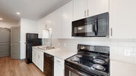 Located at 366 E Broad St in the heart of Columbus, Ohio, this single-floor unit offers a thoughtfully designed layout with modern finishes throughout. The galley-style kitchen is well-appointed with white shaker cabinetry extending to the ceiling, light-toned countertops, a subway tile backsplash, a stainless steel sink, and a full suite of black appliances including a range, over-the-range microwave, dishwasher, and refrigerator. A dedicated in-unit laundry closet houses a stacked washer and dryer, adding everyday convenience. The living and dining areas feature light wood-tone luxury vinyl plank flooring, recessed lighting, and clean white walls that create a bright, open atmosphere. Bedrooms are finished with plush carpeting, neutral tones, and sliding-door closets with built-in shelving. One bedroom benefits from a large window that invites natural light. The bathroom is spacious and finished in crisp white, featuring a walk-in shower with sliding glass doors, a white vanity with ample storage, and light wood-tone flooring that ties the space together. Throughout, the unit presents a clean, contemporary aesthetic well-suited for comfortable urban living in downtown Columbus.
