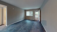 This single-floor residence offers a well-organized layout with a clean, neutral aesthetic throughout. The living area features durable hardwood-style flooring in a cool gray tone, neutral painted walls, and a glass door that welcomes natural light and provides direct outdoor access — ideal for everyday living.

The kitchen is efficiently designed with white cabinetry, a dark subway tile backsplash, granite-look countertops, and a full suite of appliances including a stainless steel gas range and black refrigerator. A double basin sink and overhead ventilation complete the functional workspace.

Multiple bedrooms are finished with plush neutral carpeting, ceiling fan fixtures, and windows fitted with vertical blinds that allow for adjustable natural light. Each room offers a comfortable, versatile space suitable for a variety of uses.

The bathroom is bright and clean, featuring a white tiled tub and shower combination, chrome fixtures, a safety grab bar, and a frosted window for natural light and privacy.

Throughout the unit, consistent HVAC venting, white trim, and a cohesive neutral color palette contribute to a unified and practical interior. The overall layout, as seen in the dollhouse view, is compact yet well-proportioned, making efficient use of every area within the single-story footprint.