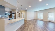 This well-appointed single-floor residence offers a thoughtfully designed open-concept layout that connects the kitchen, dining, and living areas into one cohesive, light-filled space. Warm-toned hardwood-style flooring flows throughout the main living areas, complemented by recessed lighting and large windows that invite generous natural light.

The kitchen is a standout feature, showcasing gray shaker-style cabinetry, gleaming granite countertops, a classic white subway tile backsplash, and a full suite of stainless steel appliances — including a refrigerator, range, microwave, and dishwasher. A peninsula with pendant lighting serves as both a prep area and a casual gathering spot, seamlessly connecting the kitchen to the open living space.

The bedrooms are carpeted for comfort and include ample natural light via window treatments. One bedroom features a ceiling fan and vaulted ceiling detail, while another connects to a dedicated laundry area.

The bathrooms are finished with matching gray cabinetry, granite-topped vanities, and tiled walk-in showers. The primary bathroom also includes a tall linen cabinet for additional storage. Throughout, the neutral color palette and modern finishes create a clean, contemporary ambiance well-suited for everyday living.