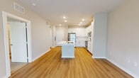 Located at 1001 Cox Grade Rd in Panama City Beach, Florida, this single-story residence offers a clean, contemporary design with a cohesive neutral color palette and modern finishes throughout. The open-concept living and kitchen area forms the heart of the space, where warm wood-style luxury vinyl plank flooring extends seamlessly across the main living zones. A central kitchen island with an integrated sink and light quartz countertop anchors the layout, providing both functional workspace and a natural gathering point.

The kitchen is well-appointed with white shaker-style cabinetry reaching toward the ceiling, a classic subway tile backsplash, light quartz countertops, and a full suite of stainless steel appliances, including a refrigerator, electric range, microwave, and dishwasher. Recessed lighting illuminates the kitchen, while the adjoining living area benefits from natural light through windows fitted with blinds and is equipped with a ceiling fan.

The bedrooms feature plush wall-to-wall carpeting and ceiling fans, with windows that bring in ample natural light. The bathroom is finished with white cabinetry, quartz countertops, brushed nickel fixtures, and a tub-shower combination. Throughout, clean white trim, recessed lighting, and a consistent neutral tone create a bright, move-in-ready environment.