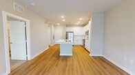 Located at 1001 Cox Grade Rd in Panama City Beach, Florida, this single-story residence offers a clean, contemporary design with a cohesive neutral color palette and modern finishes throughout. The open-concept living and kitchen area forms the heart of the space, where warm wood-style luxury vinyl plank flooring extends seamlessly across the main living zones. A central kitchen island with an integrated sink and light quartz countertop anchors the layout, providing both functional workspace and a natural gathering point.

The kitchen is well-appointed with white shaker-style cabinetry reaching toward the ceiling, a classic subway tile backsplash, light quartz countertops, and a full suite of stainless steel appliances, including a refrigerator, electric range, microwave, and dishwasher. Recessed lighting illuminates the kitchen, while the adjoining living area benefits from natural light through windows fitted with blinds and is equipped with a ceiling fan.

The bedrooms feature plush wall-to-wall carpeting and ceiling fans, with windows that bring in ample natural light. The bathroom is finished with white cabinetry, quartz countertops, brushed nickel fixtures, and a tub-shower combination. Throughout, clean white trim, recessed lighting, and a consistent neutral tone create a bright, move-in-ready environment.