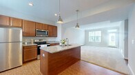 This two-story home in Plain City, Ohio offers a thoughtfully designed layout across two floors. The main level features an open-concept kitchen and living area, where warm hardwood-style flooring transitions seamlessly into carpeted living space. The kitchen is a standout, boasting rich wood cabinetry, granite countertops, a center island with a built-in sink, stainless steel appliances, and stylish pendant lighting overhead. Natural light fills the adjacent living area through a large window, creating a bright and welcoming atmosphere. The main level also includes an attached garage with an automatic opener and a dedicated laundry room with tile flooring, built-in shelving, and space for a full-size washer and dryer. Upstairs, three bedrooms offer plush carpeting and ample natural light, with the generously sized primary bedroom featuring vaulted ceiling details and its own private bathroom complete with granite countertops and a glass-enclosed shower. Additional bathrooms serve the remaining bedrooms with equal attention to finish quality. Five closets throughout the home provide excellent storage, complemented by a utility room for added functionality. With four full bathrooms, two staircases, and a hallway connecting the upper level, this home delivers a practical and comfortable living experience.