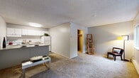 Located at 15301 NE 20th Street in Bellevue, Washington, this single-floor studio unit offers a practical and well-organized open-concept layout. The entrance foyer welcomes you with a wood-style floor accent and a large window that frames views of lush greenery outside, setting a bright and inviting tone.

The kitchen is efficiently designed with white cabinetry offering ample storage, white appliances including a refrigerator and range, a double sink, and a light-toned countertop. A peninsula with bar-height seating serves as both a functional workspace and a natural divider between the kitchen and the living area, which is finished with plush, neutral-toned carpeting throughout.

The main living space is open and versatile, benefiting from a large window that draws in natural light and provides leafy outdoor views. A walk-in closet adds meaningful storage and organization to the living area. Textured ceilings are consistent throughout the unit.

The bathroom is clean and functional, featuring a full bathtub and shower combination with chrome fixtures, a vanity with a speckled countertop, and a mirror. The walls carry a neutral gray tone that creates a calm, understated atmosphere. Overall, this unit provides a comfortable and efficient living environment in a convenient Bellevue location.