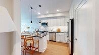 Located on the 24th floor at 7316 Wisconsin Avenue in the heart of Bethesda, Maryland, this one-bedroom, one-bathroom residence offers a well-designed layout with modern finishes throughout. Warm hardwood flooring flows seamlessly through the open-plan kitchen and living area, creating a cohesive and inviting atmosphere.

The kitchen is outfitted with white shaker cabinetry, dark countertops, a marble-style tile backsplash, and a full suite of stainless steel appliances including a gas range, dishwasher, and refrigerator. A center island with pendant lighting provides additional prep space and casual seating, making it ideal for both cooking and entertaining.

The living room is bathed in natural light through expansive floor-to-ceiling windows that frame striking high-rise views of the Bethesda skyline. The neutral palette and clean architectural lines lend the space a calm, contemporary feel.

The bedroom is a tranquil retreat, featuring large windows with the same captivating city views, light hardwood floors, and ample room for a full furniture arrangement. The bathroom is finished with classic black-and-white mosaic tile flooring, white cabinetry with brushed nickel hardware, and a clean, timeless aesthetic. Two hallways provide functional circulation and additional storage opportunities throughout the residence.