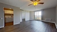 Located at 18102 66th Ct in Tinley Park, IL, this efficiently designed 1-bedroom, 1-bathroom unit offers 570 square feet of single-floor living. Throughout the space, durable hardwood-style flooring in a warm gray-brown tone provides a cohesive and modern aesthetic complemented by neutral gray walls and white trim.

The living room is a bright, open area featuring a ceiling fan, a large sliding glass door that opens to a private balcony with outdoor views, and baseboard heating with a wall-mounted AC unit for year-round climate control. Built-in floor-to-ceiling white cabinetry along one wall provides generous storage without sacrificing floor space.

The bedroom, spanning 160 square feet, offers ample room and includes additional built-in closet storage, a window for natural light, baseboard heating, and a sliding barn-style door. A compact kitchen with stainless steel appliances connects to the main living area.

The bathroom is cleanly finished with a white tile tub-and-shower surround, a white vanity with light stone countertop, hardwood-style flooring, and stainless steel grab bars, adding both practicality and safety. The overall layout is efficient and well-organized, making this unit a functional and comfortable living space.