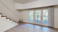 This two-story home in Wyoming, Michigan offers three bedrooms, three bathrooms, and a thoughtfully designed layout spread across two floors. The expansive main level hosts an open-concept living, dining, and kitchen area anchored by light hardwood-style flooring. The kitchen is well-appointed with dark walnut-toned shaker cabinetry, white subway tile backsplash, white quartz countertops, stainless steel appliances including a gas range and refrigerator, and a peninsula with pendant lighting — ideal for both cooking and casual dining. The living area features soaring ceilings and is bathed in natural light from large French doors that open to a private balcony overlooking lush, mature trees. A staircase with white balusters leads to the upper level. The generously sized primary bedroom boasts vaulted ceilings, plush carpeting, and a walk-in closet. Additional bedrooms are carpeted and offer natural light and closet storage. The bathrooms are finished with warm wood vanities, quartz countertops, and light wood-look tile flooring. With six closets throughout, storage is plentiful. The home's clean, neutral palette and modern finishes create a bright, move-in-ready atmosphere.