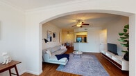 Located at 1701 Ennis Joslin Rd in Corpus Christi, Texas, this single-floor residence combines classic architectural details with a functional, comfortable layout. Distinctive arched doorways frame the open-concept living and dining areas, lending an elegant, cohesive aesthetic throughout the main living spaces. Rich hardwood-style flooring runs through the living, dining, and kitchen areas, while crown molding and ceiling fans add a refined finishing touch.

The living room is generously proportioned, bathed in natural light from large windows, and anchored by a ceiling fan overhead. It connects seamlessly through an arched passageway to the dining area, which features a dedicated dining nook with a pendant light fixture. The kitchen offers warm wood cabinetry, ample counter space, a full-size refrigerator, and a pass-through that maintains an open connection to the living and dining spaces. Built-in shelving niches add both character and practicality to the hallways.

The bedrooms are carpeted and well-sized, each offering a calm, restful atmosphere. The bathroom is thoughtfully designed with dual sinks, rich wood cabinetry, a large mirror, and a separate shower and tub area. A dedicated in-unit laundry closet with a full washer and dryer rounds out the practical amenities of this well-designed Corpus Christi residence.