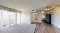 Located at 121 Kokomo St in Colorado Springs, CO, this 2-bedroom, 1-bathroom single-floor residence offers a practical and comfortable layout. The living area features a combination of plush carpet and wood-style flooring, a ceiling fan, and a large sliding glass door covered by vertical blinds that fills the space with natural light. The kitchen is laid out in a galley style with wood-style flooring, light cabinetry, and black appliances including a full-size refrigerator and range. Both bedrooms are carpeted and feature textured ceilings, closets with bi-fold doors, and windows that allow for natural light and outdoor views. The primary bedroom offers a generous layout with its own closet and convenient access to the hallway. The bathroom includes a white vanity with under-cabinet storage, a medicine cabinet mirror, and wood-style flooring. Neutral warm tones are carried throughout the unit, creating a cohesive and understated aesthetic. The overall layout is efficiently designed, making good use of the available floor space across each room.