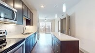 This contemporary one-bedroom apartment at Central Square at Frisco offers 560 square feet of thoughtfully designed living space. The layout maximizes functionality with a 110 square foot primary bedroom, a full bathroom, and an open-concept kitchen and living area. The bathroom boasts a sleek design with a large vanity, ample storage, and a tiled shower. The kitchen is a highlight, featuring dark wood cabinetry, stainless steel appliances, and a central island, all complemented by warm wood-tone flooring. The bedroom, while compact, offers plush carpeting and large windows that flood the space with natural light. Throughout the apartment, neutral tones create a bright, airy atmosphere. A standout feature is the generous closet space, ensuring ample storage. The apartment's design emphasizes clean lines and modern finishes, creating a sophisticated urban living experience in a compact, efficient space.