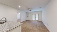 Located at 8240 Windsor Hill Blvd in North Charleston, SC, this one-bedroom, one-bathroom residence offers a well-designed single-floor layout that maximizes comfort and functionality. The open-concept kitchen and living area serves as the heart of the home, where the kitchen stands out with crisp white shaker cabinets, granite countertops, a subway tile backsplash, and a full suite of stainless steel appliances including a refrigerator, range, and microwave. A peninsula with an integrated sink and breakfast bar seating bridges the kitchen to the living area, which features plush wall-to-wall carpeting, a ceiling fan, and French doors that invite natural light and provide outdoor access. The spacious primary bedroom is generously sized, carpeted for comfort, and equipped with its own ceiling fan and a window for natural light. A walk-in closet with wire shelving offers ample storage. The bathroom is finished with a granite-topped white vanity, a framed mirror, and a full tub-shower combination with tile surround, all set on light wood-tone flooring. Throughout the residence, neutral tones and clean finishes create a bright, welcoming ambiance well-suited to everyday living.