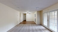 Located at 700 22nd Ave in Phenix City, Alabama, this single-story, one-bedroom, one-bathroom home offers a practical and well-organized layout across its single floor. The open-concept living and dining area serves as the heart of the home, featuring warm wood-look laminate flooring, neutral cream-toned walls, a ceiling fan with light fixture, and a textured ceiling throughout. Natural light filters in through slatted blinds on the windows and a glass-panel door, creating a bright and airy atmosphere. The galley-style kitchen is efficiently designed with dark gray cabinetry on both sides, light countertops, a stainless steel sink, and black appliances including a full-size refrigerator. The spacious bedroom is carpeted for comfort and includes a ceiling fan, ample natural light from a window, and direct access to the hallway leading to the bathroom. The bathroom features wood-look flooring, a dark-stained vanity with a framed mirror, a three-bulb vanity light, and a closet nearby. Additional highlights include multiple closets for storage, a dedicated laundry area, a utility room, and connecting hallways that keep the floor plan flowing efficiently throughout.