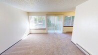 Located at 5715 N 30th St in Tacoma, WA, this one-bedroom, one-bathroom unit offers a efficiently designed single-floor layout. The living room is a bright, open space featuring wall-to-wall carpeting, a textured ceiling, a baseboard heater, and multiple windows with vertical and horizontal blinds that invite natural light and views of the surrounding greenery. A sliding glass door adds outdoor connectivity and further enhances the sense of openness. The combined dining and kitchen area is a functional galley-style space finished with light tile flooring. It features warm wood cabinetry, dark granite-style countertops, a stainless steel sink, and white appliances including a refrigerator, range, and dishwasher. The bedroom is a comfortable, carpeted room with a window overlooking outdoor greenery, a baseboard heater, a textured ceiling, and a dedicated closet with a sliding wood panel door and hanging rod. An additional closet provides supplementary storage elsewhere in the unit. The bathroom includes tile flooring, a dark-toned vanity with an integrated sink, a full tub/shower combo, and a toilet, all finished in clean white tones. Throughout the unit, warm neutral walls and consistent trim details contribute to a cohesive, understated aesthetic.