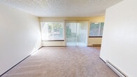 Located at 5715 N 30th St in Tacoma, WA, this one-bedroom, one-bathroom unit offers a efficiently designed single-floor layout. The living room is a bright, open space featuring wall-to-wall carpeting, a textured ceiling, a baseboard heater, and multiple windows with vertical and horizontal blinds that invite natural light and views of the surrounding greenery. A sliding glass door adds outdoor connectivity and further enhances the sense of openness. The combined dining and kitchen area is a functional galley-style space finished with light tile flooring. It features warm wood cabinetry, dark granite-style countertops, a stainless steel sink, and white appliances including a refrigerator, range, and dishwasher. The bedroom is a comfortable, carpeted room with a window overlooking outdoor greenery, a baseboard heater, a textured ceiling, and a dedicated closet with a sliding wood panel door and hanging rod. An additional closet provides supplementary storage elsewhere in the unit. The bathroom includes tile flooring, a dark-toned vanity with an integrated sink, a full tub/shower combo, and a toilet, all finished in clean white tones. Throughout the unit, warm neutral walls and consistent trim details contribute to a cohesive, understated aesthetic.