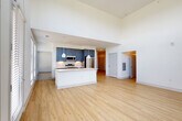 Located at 7400 S Addison Ct in Aurora, CO, this thoughtfully designed 2-bedroom, 2-bathroom residence offers a clean, contemporary aesthetic across a single floor. The open-concept kitchen and living area serves as the heart of the home, featuring soaring ceilings with tall clerestory windows that flood the space with abundant natural light. The kitchen is outfitted with slate-blue cabinetry, a subway tile backsplash, stainless steel appliances including a refrigerator, microwave, and range, and a central island with a white quartz countertop, undermount sink, and stylish pendant lighting. Light-toned hardwood-style flooring extends throughout the main living areas, enhancing the bright, airy atmosphere. Both bedrooms offer plush carpeting, ceiling fans, and generous natural light from large windows with views of the surrounding greenery. The primary bedroom includes its own closet access. The bathrooms are well-appointed, with one featuring a glass-enclosed walk-in shower with marble-style tile surround and a dark vanity with dual sinks. Additional spaces include four closets, a dedicated laundry area, a utility room, and a connecting hallway, ensuring practical functionality throughout. The overall design balances modern style with comfortable, everyday livability.