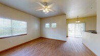 Located at 1000 Diamond Dr in Boerne, Texas, this two-story residence offers a well-designed layout with practical finishes throughout. The main living area is open and airy, featuring warm wood-look flooring, a ceiling fan with light kit, and multiple windows dressed with blinds that invite natural light. A sliding glass door connects the living space to the outdoors, enhancing the sense of openness. The adjoining dining area flows naturally from the living room, illuminated by a hanging pendant light fixture.

The kitchen is efficiently arranged with light wood cabinetry, dark granite-style countertops, white appliances including a refrigerator, electric range, built-in microwave, and dishwasher. A breakfast bar provides additional counter space and a casual dining option. A dedicated interior door leads to a pantry or utility closet area.

A bathroom features a tiled shower-tub combination, wood cabinetry overhead, dark countertops at the vanity, and large mirrors. A convenient stacked washer and dryer unit is accessible nearby, adding in-unit laundry functionality.

The bedroom is carpeted for comfort, equipped with a ceiling fan, a natural window view, and a spacious reach-in closet. A staircase connects the two floors, offering additional living or storage space above.
