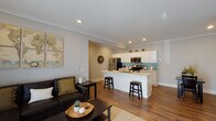 This single-floor residence offers a thoughtfully designed open-concept layout that seamlessly connects the living, dining, and kitchen areas. The living room is bright and welcoming, featuring a wall-mounted mini-split climate system, sliding glass doors that allow abundant natural light, and crown molding that adds a refined architectural touch.

The kitchen is a standout feature, showcasing white shaker cabinetry extending to the ceiling, a teal subway tile backsplash, stainless steel appliances including a refrigerator, range, and built-in microwave, and a spacious white quartz peninsula with an undermount sink and bar seating — ideal for casual dining or entertaining.

Warm hardwood-style flooring runs throughout the unit, creating a cohesive and inviting atmosphere. A hallway connects the main living area to two well-sized bedrooms. The primary bedroom includes a mirrored sliding-door closet, while a secondary bedroom offers a wall-mounted climate unit and a serene, neutral palette. The primary bathroom features a dual-sink white vanity, wood-framed mirrors, and a tiled walk-in shower. A second full bathroom with a white vanity and hardwood-style flooring provides additional convenience. Recessed lighting and crown molding are consistent throughout, lending the space a clean, polished character.