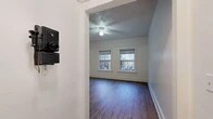 Located at 1025 SW 11th Ave in Portland, Oregon, this single-floor unit offers a practical and well-organized layout spread across several interconnected rooms. The living area features dark hardwood-style flooring, white-trimmed windows that frame street views, and a ceiling fan overhead. Two side-by-side windows allow natural light to filter in, creating a bright and open atmosphere.

The bedroom areas are finished with lighter hardwood-style flooring, clean white walls, and classic panel-style doors with brass hardware. One bedroom includes a cast-iron radiator beneath a window, a nod to the building's older architectural character. The rooms provide a neutral, versatile backdrop suitable for a variety of furnishing arrangements.

The kitchen is compact and functional, equipped with a white gas range and dark cabinetry with modern hardware. A bold black-and-white checkered tile floor adds a classic aesthetic touch, echoed in the bathroom. The bathroom continues this vintage-inspired design with matching checkered flooring, a clawfoot-style bathtub, a wood-toned vanity, and white panel walls. A window provides ventilation and natural light. Throughout the unit, the consistent use of white walls and natural-toned flooring creates a cohesive, clean aesthetic.