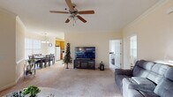 Located at 901 Falls Park Dr in Sanford, NC, this single-story home offers a functional and comfortable layout designed for everyday living. The spacious living room serves as the heart of the home, featuring plush carpeting, crown molding, a ceiling fan, and open sightlines connecting to the dining area. A set of glass doors in the adjoining sitting area fills the space with natural light and provides outdoor access. The dining area is finished with tile flooring, wainscoting, and a pendant light fixture above the table, while a window with blinds allows for natural light. The kitchen is equipped with warm wood cabinetry, ample counter space, a stainless steel sink, a dishwasher, and a window that brings in additional daylight. The bedrooms are carpeted and well-sized, each offering closet space and windows with blinds; one bedroom features a ceiling fan for added comfort. The full bathroom includes a wood-toned vanity, a wide mirror, tile flooring, and a tub-shower combination. A dedicated laundry area houses a full-size washer and dryer with overhead shelving for storage. Throughout the home, neutral tones and consistent finishes create a cohesive and welcoming atmosphere.