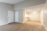 Located at 2300 Fairview Rd in Costa Mesa, California, this single-floor residence offers a well-organized layout with a warm, neutral color palette carried throughout. The living area is a standout feature, boasting dramatic vaulted ceilings that create a sense of expansive volume and openness. Soft carpeting covers the floor, adding comfort underfoot, while a large sliding glass door fitted with vertical blinds floods the space with natural light and provides outdoor views. A wall-mounted HVAC unit and a ceiling fan contribute to year-round climate comfort. The kitchen is efficiently designed with white cabinetry offering ample storage, light-toned laminate countertops, a double-basin sink, a dishwasher, an electric range with overhead ventilation hood, and durable hardwood-style flooring. The bedrooms continue the carpeted, neutral aesthetic, with textured ceilings and access to closet space. The bathroom features a full shower-tub combination with chrome fixtures and a clean white finish. Throughout the home, white trim and baseboards provide a crisp contrast to the warm beige walls, contributing to a cohesive and tidy interior feel well-suited to everyday living in the heart of Orange County.