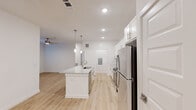 Located at 13030 Perry Road in Houston, TX 77070, this well-appointed single-story, 3-bedroom, 2-bathroom home offers a clean, modern aesthetic throughout. Light hardwood flooring runs continuously across all rooms, creating a bright and cohesive feel.

The open-concept kitchen is a standout feature, showcasing white shaker cabinetry, granite countertops, a herringbone tile backsplash, and a full suite of stainless steel appliances including a refrigerator, range, and microwave. A central island with an undermount sink and pendant lighting above connects seamlessly to the living area, which is equipped with a ceiling fan.

The primary bedroom offers a comfortable retreat with natural light from dual windows and direct access to an en-suite bathroom featuring a dual-sink granite vanity, white cabinetry with brushed nickel hardware, and a tiled walk-in shower. The second full bathroom mirrors the same refined finishes with a dual-sink vanity and granite countertops.

The two additional bedrooms are bright and versatile, each with light-filled windows and ceiling fans. Three closets provide ample storage throughout. A dedicated laundry area houses a full-size washer and dryer. The home's neutral white walls and consistent modern finishes create a clean, move-in ready environment.