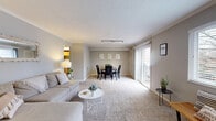 Located at 7950 Village Drive in Cincinnati, OH, this single-floor, 2-bedroom, 2-bathroom home offers a well-organized layout designed for comfortable everyday living. The combined living and dining area forms the heart of the home, featuring plush carpeting, neutral gray tones, crown molding, and large windows that invite natural light. Track lighting accents the dining area, while a sliding glass door leads directly to a private balcony overlooking a lush, wooded landscape — a serene outdoor retreat. The kitchen is outfitted with warm oak cabinetry, granite-look countertops, hardwood-style flooring, and black appliances including a refrigerator, dishwasher, and range. Both bedrooms are carpeted and well-lit by wide windows with views of the surrounding greenery. The spacious primary bedroom offers ample room for large furnishings, while the second bedroom provides a bright, comfortable alternative. Two full bathrooms feature oak vanities, white fixtures, and hardwood-style flooring. A central hallway connects all areas of the home, lined with five closets offering exceptional storage throughout. The private balcony completes this home with peaceful outdoor views of mature trees and open green space.