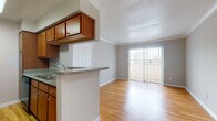 This single-floor, one-bedroom, one-bathroom residence offers a thoughtfully designed layout that maximizes functionality throughout. The open living area features light-toned hardwood flooring and neutral gray walls accented by crown molding, creating a clean and cohesive aesthetic. A sliding glass door floods the space with natural light and provides direct access to a private balcony, extending the living area outdoors.

The galley-style kitchen is efficiently arranged with warm wood cabinetry offering ample storage, granite-style countertops, and black appliances including a range, microwave, and refrigerator. A peninsula with a built-in sink separates the kitchen from the dining area, which is defined by a pendant light fixture overhead.

The bedroom provides a comfortable retreat with plush carpeting, neutral walls, and a window with blinds that allows for natural light. A walk-in closet adjacent to the room adds valuable storage capacity.

The bathroom features hardwood flooring, a wood vanity with a granite-style countertop, and a full tub-shower combination with white tile surround. Throughout the unit, consistent finishes and a neutral color palette create a cohesive and inviting atmosphere.