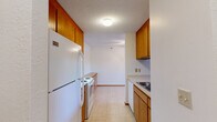 Located at 33 County Road C E in Little Canada, MN, this one-bedroom, one-bathroom unit offers a practical and comfortable single-floor layout. The galley-style kitchen is efficiently designed with warm wood cabinetry lining both sides, providing ample upper and lower storage. White appliances including a refrigerator, electric range, and dishwasher are neatly integrated, and light tile flooring adds a clean, functional finish. The kitchen opens into a combined dining area, creating a natural flow for daily living. The carpeted living room is generously proportioned, featuring a large sliding glass door that introduces natural light and provides access to a private balcony with outdoor views. A hallway connects the main living areas to the bedroom, bathroom, and two closets. The bedroom is well-sized, featuring carpet flooring, a baseboard heating unit, and a window with a blind that allows natural light while maintaining privacy. The bathroom includes a full tub-and-shower combination with built-in shelving, white tile accents, and mosaic tile flooring. Textured ceilings are consistent throughout, and warm wood baseboards add a cohesive finishing detail across the unit.